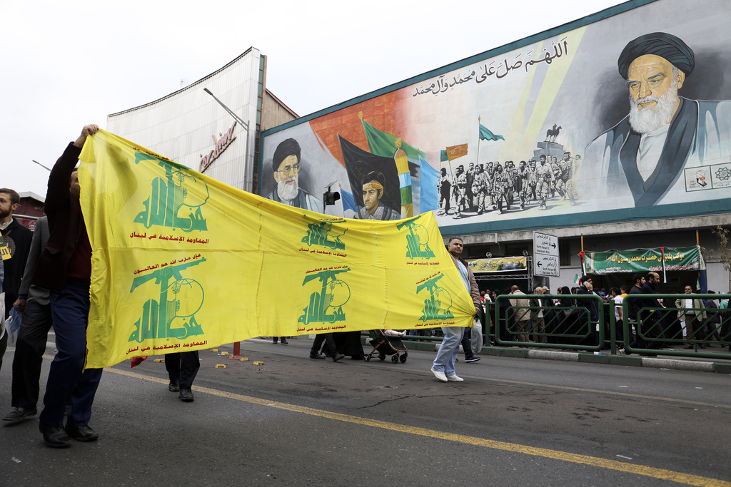Iranian Muslims carry a banner with flags of Lebanese militant group Hezbollah at pro-Palestinian rally in Tehran, Iran, Friday, Oct. 13, 2023.