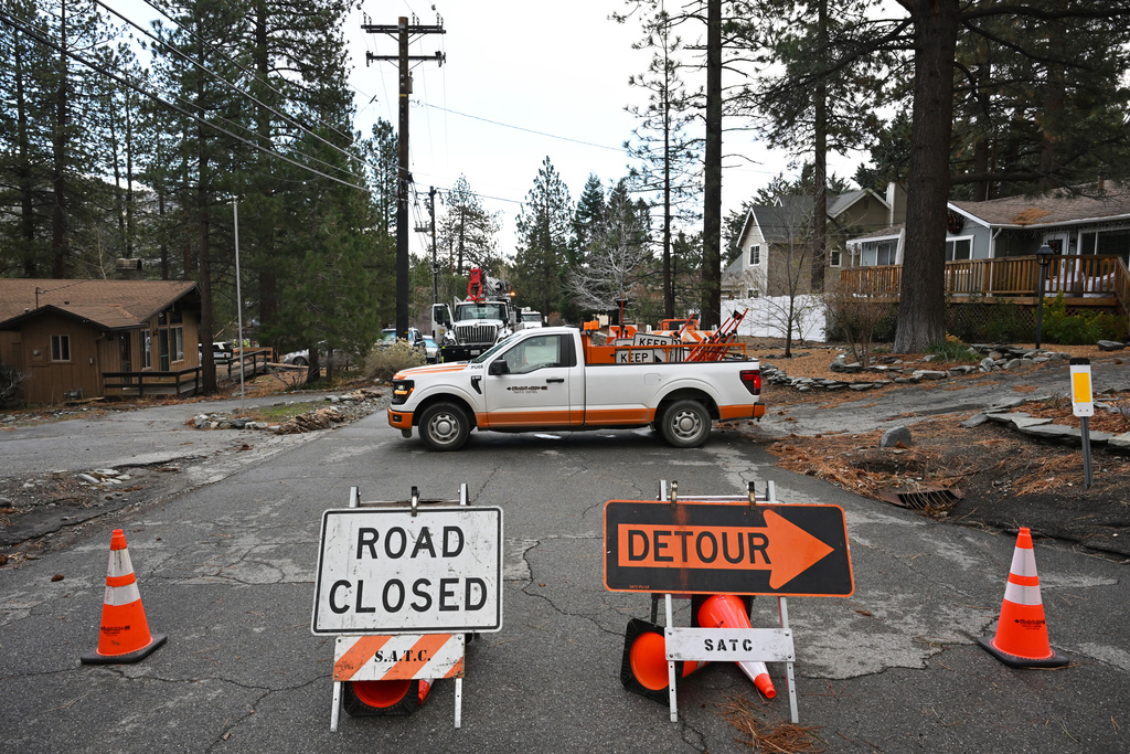 Workers work to restore power after severe storms, Thursday, Dec. 25, 2025, in Wrightwood, Calif. (AP Photo/William Liang)