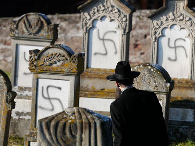 In this Dec. 4, 2019 file photo, Strasbourg chief Rabbi Harold Abraham Weill looks at vandalized tombs in the Jewish cemetery of Westhoffen in eastern France.  (AP Photo/Jean-Francois Badias, File)
