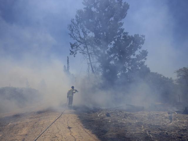 An Israeli firefighter attempts to extinguish a fire caused by an incendiary balloon launched by Palestinians from the Gaza Strip, on the Israel-Gaza border, Israel, Tuesday, June 15, 2021. (AP Photo/Tsafrir Abayov)