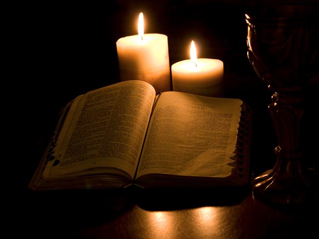 dark background and a Bible with candlelight