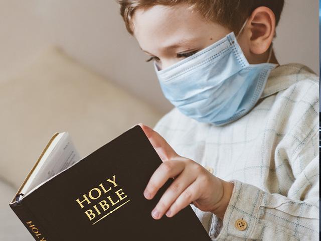 child wearing surgical mask reading the Bible