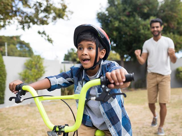 child with father learning to ride a bicycle
