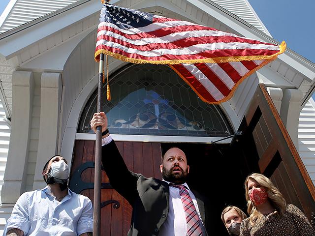 Adams Sq. Baptist Church Pastor Kris Casey waves an American flag after opening his church doors for Sunday service on May 3, 2020 in Worcester, Mass. (Nancy Lane/The Boston Herald via AP)