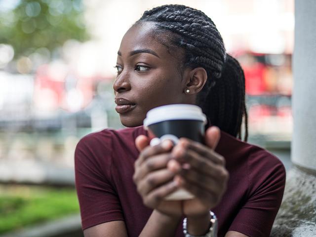 woman holding a cup of coffee and thinking about something