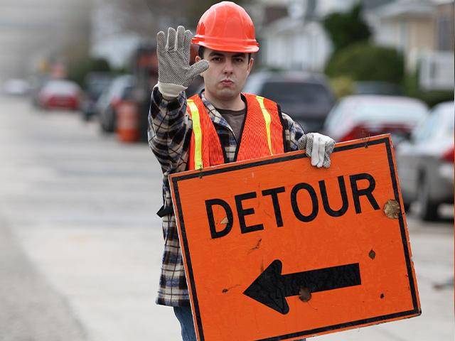 construction worker holding detour sign