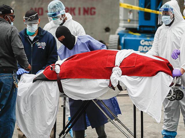 A body wrapped in plastic that was unloaded from a refrigerated truck is handled by medical workers wearing personal protective equipment due to COVID-19 concerns, Tuesday, March 31, 2020, at Brooklyn Hospital Center in New York. (AP Photo/John Minchillo)