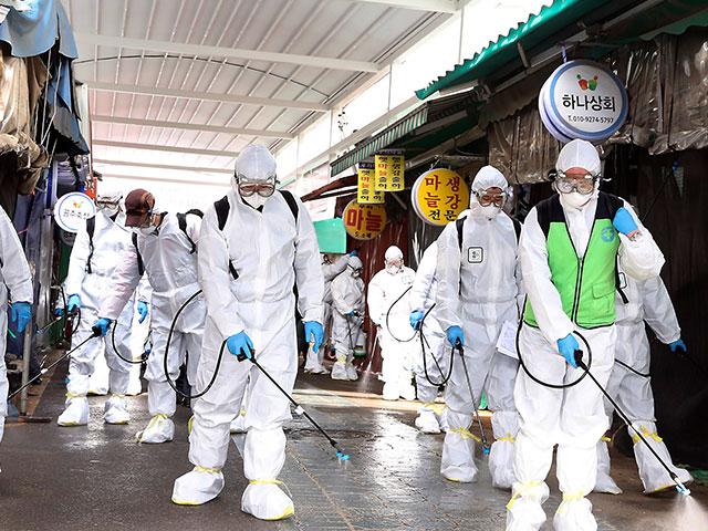 Workers wearing protective suits spray disinfectant as a precaution against the coronavirus at a market in Bupyeong, South Korea, Monday, Feb. 24, 2020. South Korea reported another large jump in new virus cases Feb. 24 (Lee Jong-chul/Newsis via AP)