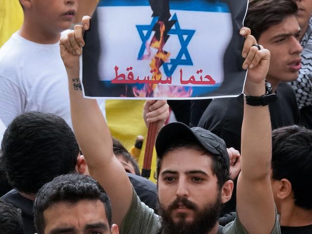 A Hezbollah supporter holds up an Arabic placard that reads:"It will definitely fall," during a protest to show their solidarity with the Palestinians, in the southern suburb of Beirut, Lebanon, Friday, Oct. 13, 2023. (AP Photo/Hussein Malla)