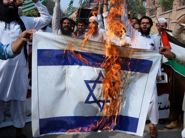 Pakistanis burn an Israeli flag in Peshawar, Friday, Oct.13, 2023. (AP Photo/Muhammad Sajjad)
