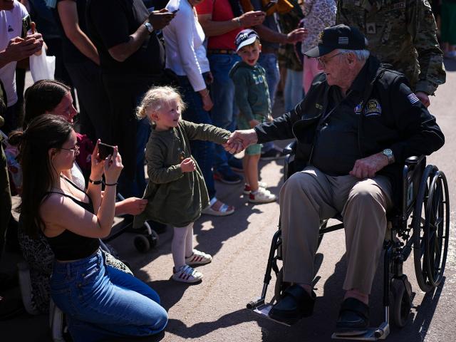 U.S. WW II veteran Warren Morrison is greeted by a little girl during a veterans parade in Sainte-Mere-Eglise, Normandy, France, June 5, 2024 (AP Photo/Daniel Cole)