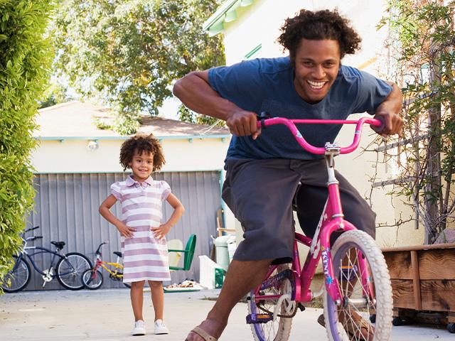 father grinning while playfully riding his daughter