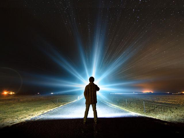 boy with flashlight walking down dark road