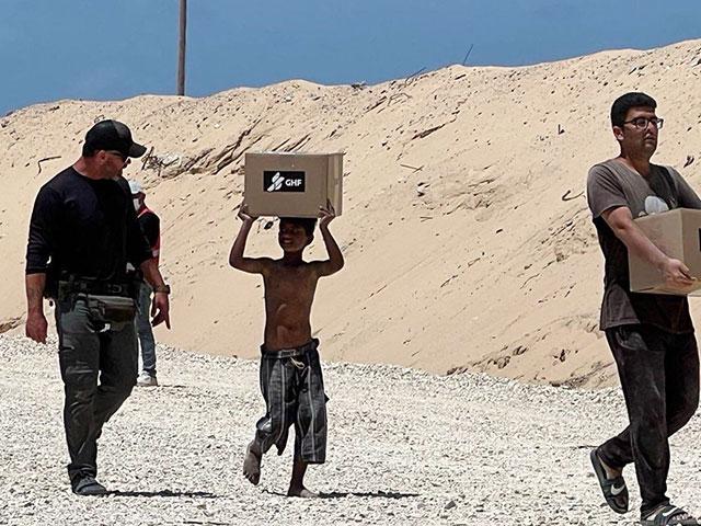 A Gazan boy carries a box of humanitarian aid. Photo Credit: Gaza Humanitarian Foundation (GHF).