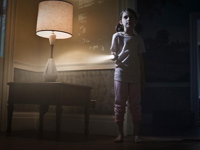 young girl in a dimly lit room with a table lamp
