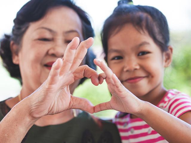 grandmother and child making heart sign together with their fingers