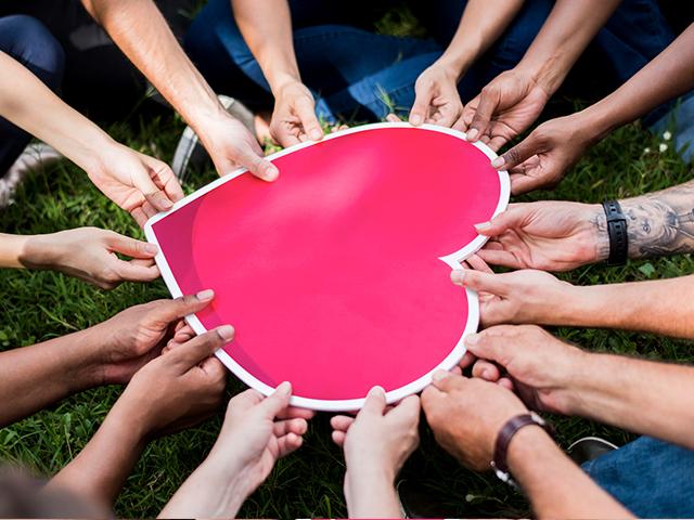 group of people holding a big heart