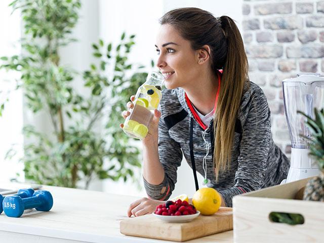 healthy young woman drinking water with lemon