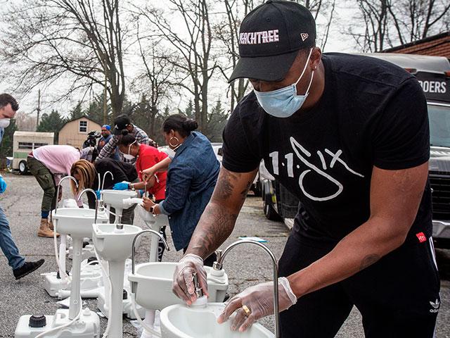 Grammy award-winning hip hop artist Lecrae assembles a portable wash station in College Park, Georgia. The wash stations were distributed by Lecrae and volunteers with Love Beyond Walls. (AP Photo/ Ron Harris)