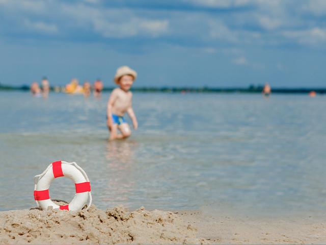lifebuoy on beach and young boy in the shallow water