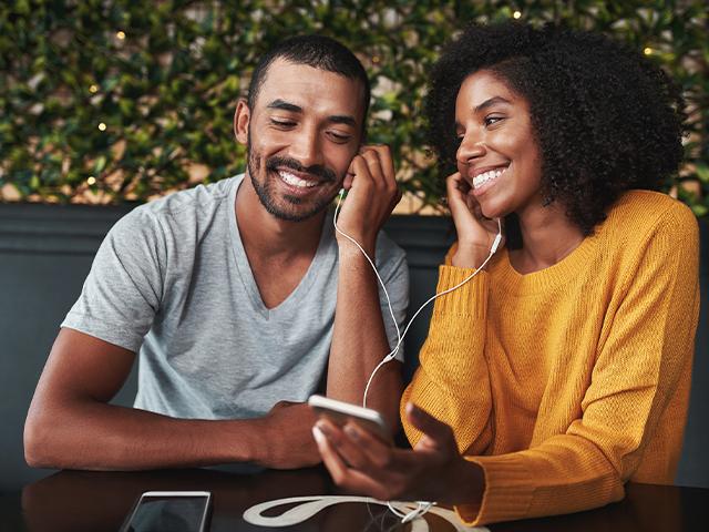 couple wearing earbuds listening to something together