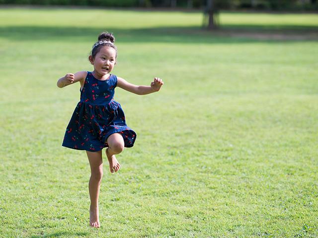 little girl skipping in the green grass
