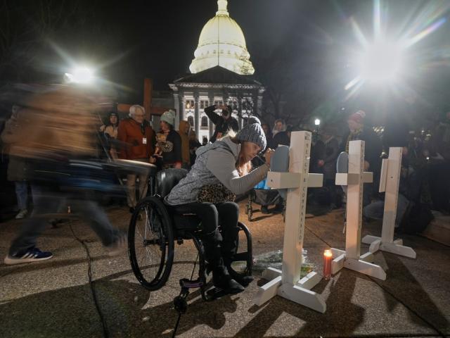 A supporter signs a cross during a candlelight vigil Tuesday, Dec. 17, 2024, outside the Wisconsin Capitol in Madison, Wis., following a shooting at the Abundant Life Christian School on Monday, Dec. 16. (AP Photo/Morry Gash)