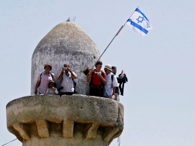 Jewish settlers and opponents of Israeli Prime Minister Ariel Sharon&#039;s plan to pull out of the Gaza Strip and four West Bank settlements stand atop a minaret in the northern West Bank settlement of Sa Nur, Thursday April 28, 2005. (AP Photo/Ariel Schalit)