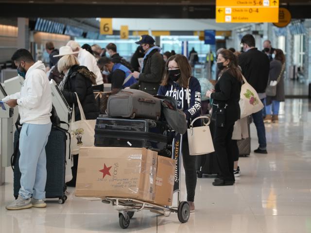 Travelers queue up at the United American Airlines check-in kiosks in the terminal of Denver International Airport Sunday, Dec. 26, 2021, 
