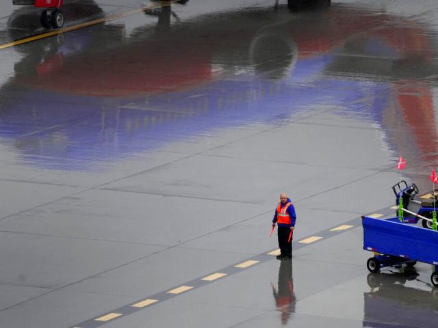 A Southwest Airlines ground operations crew member waits to guide an arriving jet into a gate, Wednesday, Dec. 28, 2022, at Sky Harbor International Airport in Phoenix. (AP Photo/Matt York)