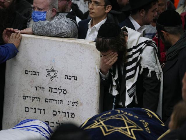 Mourners gather around the bodies of Israeli couple Eli Mizrahi and his wife, Natalie, victims of a shooting attack Friday in Jerusalem, during their funeral at the cemetery in Beit Shemesh, Israel, early Sunday, Jan. 29, 2023. (AP Photo/Ariel Schalit)