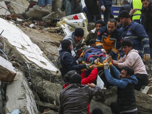 People and emergency teams rescue a person on a stretcher from a collapsed building in Adana, Turkey, Monday, Feb. 6, 2023. A powerful quake has knocked down multiple buildings in southeast Turkey and Syria. (IHA agency via AP)