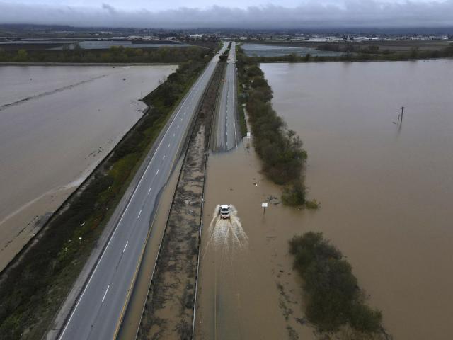 A CalTrans vehicle drives north through floodwaters that closed state Highway 1 at the Santa Cruz County line, in California, Sunday, March 12, 2023. (Shmuel Thaler/The Santa Cruz Sentinel via AP)
