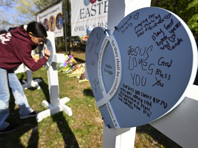 A youngster writes a message on crosses at an entry to Covenant School, Tuesday, March 28, 2023, in Nashville, Tenn., which has become a memorial to the victims of Monday&#039;s school shooting. (AP Photo/John Amis)
