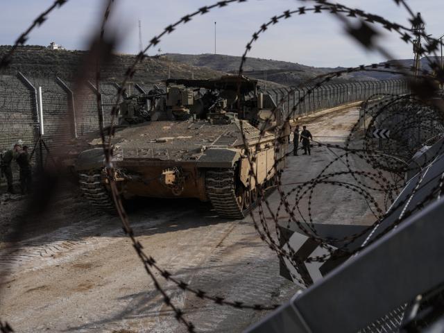 Israeli soldiers stand next to armored vehicles parked near the so-called Alpha Line that separates the Israeli-annexed Golan Heights from Syria, in the town of Majdal Shams, Monday, Dec. 9, 2024. (AP Photo/Matias Delacroix)