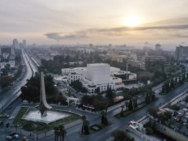 An aerial view shows a column of black smoke in the background, allegedly caused by an Israeli airstrike, as seen from Umayyad square in Damascus, Syria, Tuesday, Dec. 10, 2024.(AP Photo/Ghaith Alsayed)