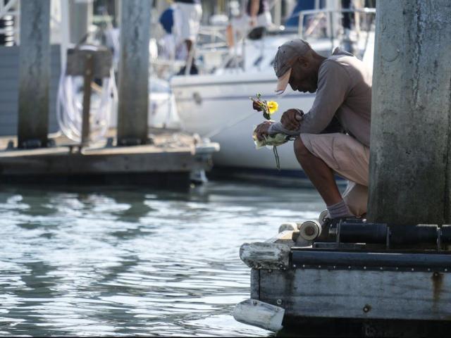 James Miranda, right, of Santa Barbara, holds flowers and takes a moment to reflect at a dock near the Sea Landing at Santa Barbara Harbor in Santa Barbara, Calif., Monday, Sept. 2, 2019. (AP Photo/Ringo H.W. Chiu) 