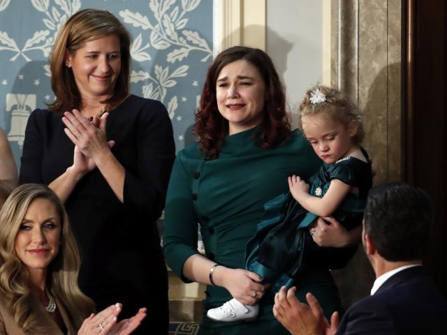 Robin Schneider of Kansas City, Mo., holds her daughter Ellie as President Donald Trump recognizes them during his State of the Union address, Feb. 4, 2020. (AP Photo/Alex Brandon)