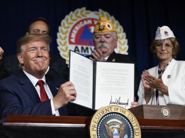 President Donald Trump holds up a presidential memorandum that he signed that discharges the federal student loan debt of totally and permanently disabled veterans. (AP Photo/Susan Walsh) 