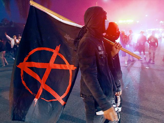 A man carries a flag depicting the anarchist symbol during a protest over the death of George Floyd, May 30, 2020, in Los Angeles. (AP Photo/Chris Pizzello)