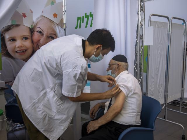 A man receives a third Pfizer-BioNTech COVID-19 vaccine from medical staff at a coronavirus vaccination center in Tel Aviv, Israel, Tuesday, Aug. 10, 2021. Israel is grappling with a surge of infections and urging people over age 60 to get a booster shot.