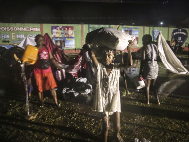 People affected by Saturday&#039;s earthquake recover their belongings under the rain of Tropical Depression Grace at a refugee camp in Les Cayes, Haiti, Monday, Aug. 16, 2021. (AP Photo/Joseph Odelyn)