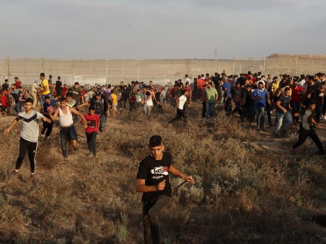 Protestors run to cover from teargas fired by Israeli troops near the Gaza Strip border amid violent riots. Saturday, Aug. 21, 2021. (AP Photo/Adel Hana)
