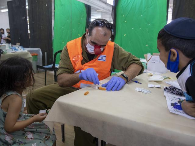 An Israeli soldier conducts a COVID-19 antibody test on a child in Hadera, Israel, Monday, Aug. 23, 2021. (AP Photo/Ariel Schalit)
