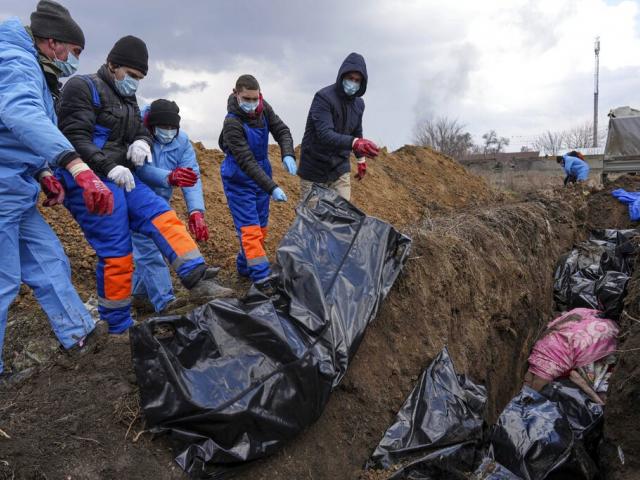 Dead bodies are placed into a mass grave on the outskirts of Mariupol, Ukraine, Wednesday, March 9, 2022 as people cannot bury their dead because of the heavy shelling by Russian forces. (AP Photo/Evgeniy Maloletka)