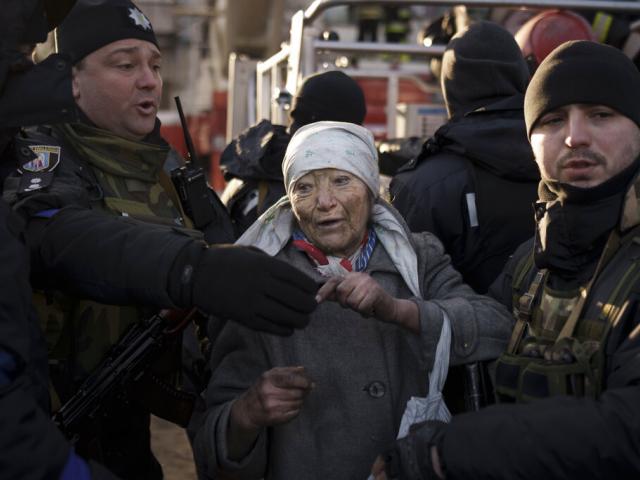 An elderly woman is helped by policemen after she was rescued by firefighters from inside her apartment after bombing in Kyiv, Ukraine, Tuesday, March 15, 2022. (AP Photo)