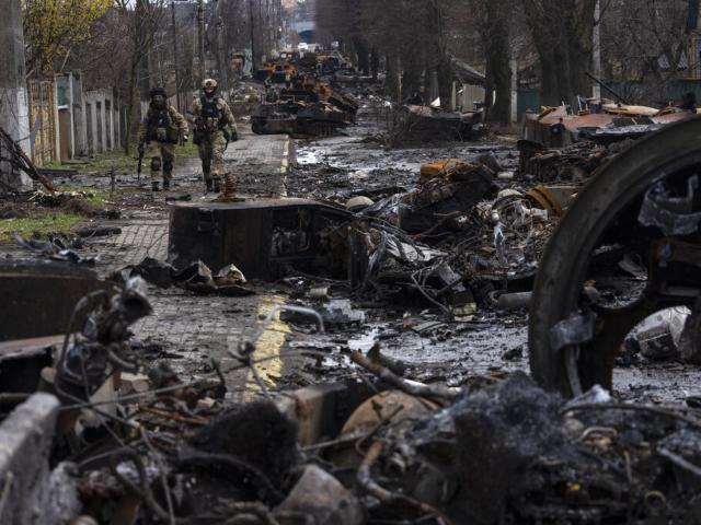 Soldiers walk amid destroyed Russian tanks in Bucha, in the outskirts of Kyiv, Ukraine, Sunday, April 3, 2022. (AP Photo/Rodrigo Abd)