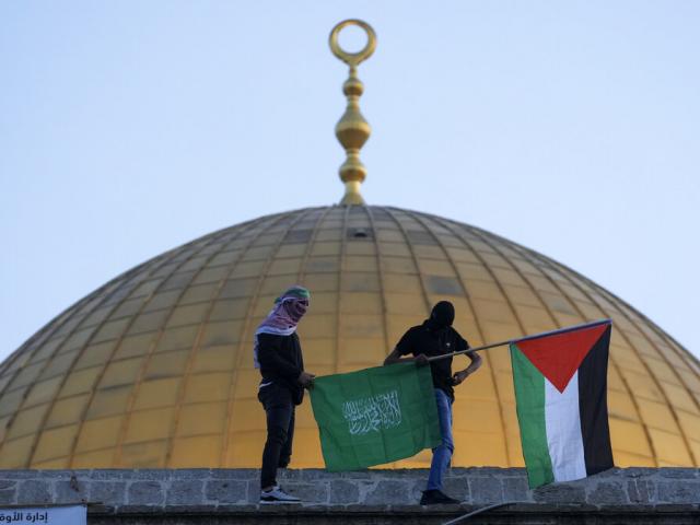 Masked Palestinians carry Palestinian and Hamas flags during Eid al-Fitr celebrations next to the next to the Dome of the Rock Mosque. AP Photo.