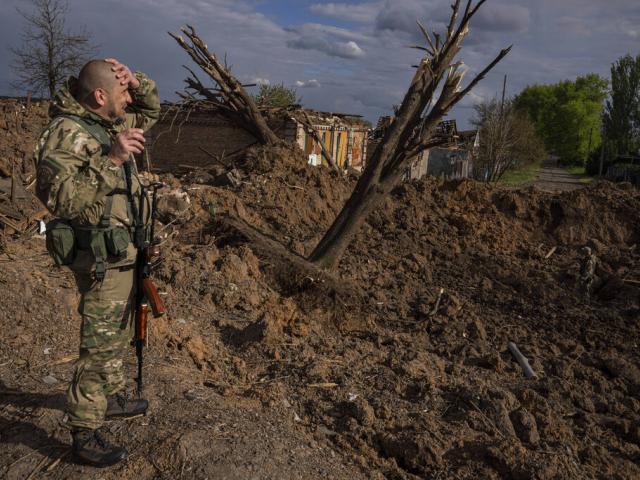 A Ukrainian serviceman inspects a site after an airstrike by Russian forces in Bahmut, Ukraine, Tuesday, May 10, 2022. (AP Photo/Evgeniy Maloletka)