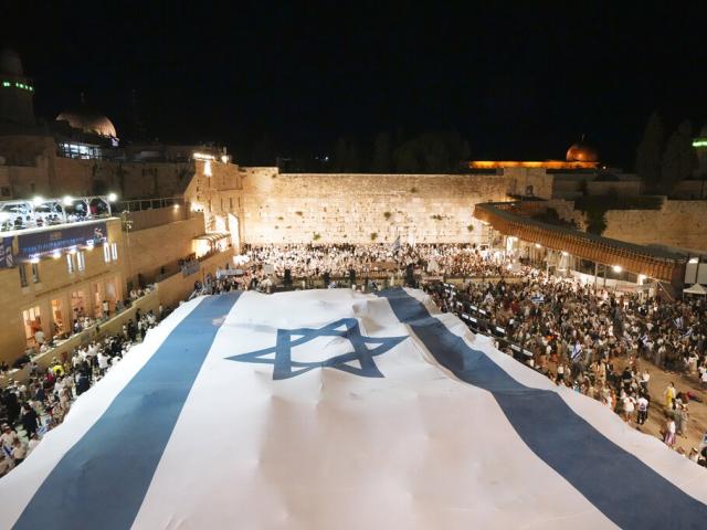 Members of Jewish youth movements unfurl a giant Israeli flag on the eve of Jerusalem Day. (AP Photo)